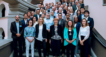 Grupo de participantes de reunión de investigación en encuentro de U21 en una escalera.