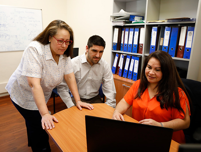 Grupo de administrativos trabajan juntos frente a un computador 
