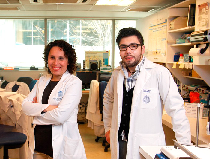 Javier Cerda junto a la profesora Viviana Montecinos usando delantal blanco en un laboratorio