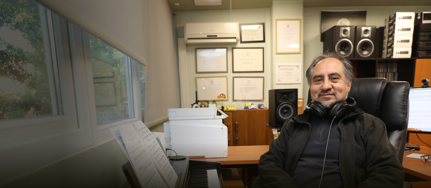 El profesor Rodrigo Cádiz en su oficina sentado junto a un piano.
