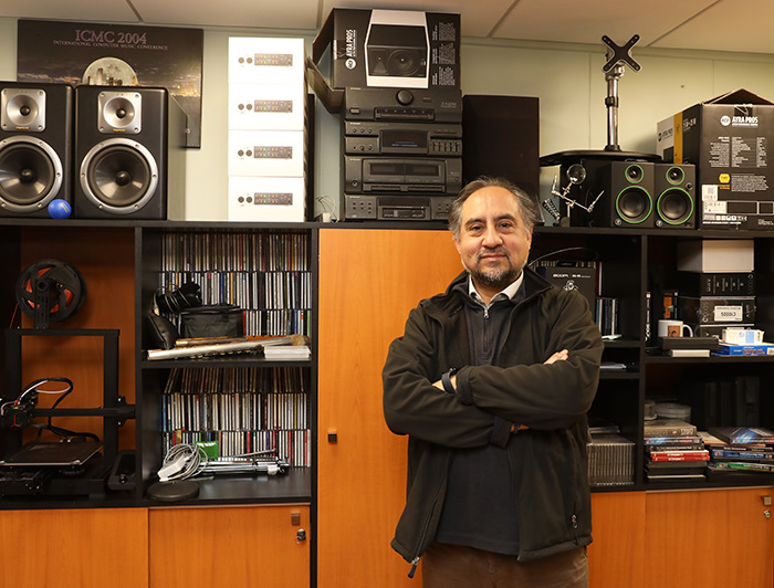 El profesor Rodrigo Cádiz en su oficina, delante de un mueble repleto de equipos, cd's, impresora láser, entre otras cosas.