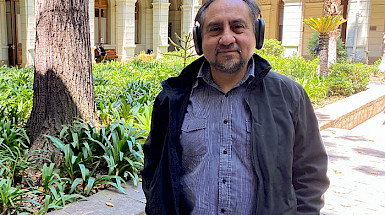 El profesor Rodrigo Cádiz de pie llevando sus audífonos puestos, en un patio de Casa Central de la Universidad Católica.