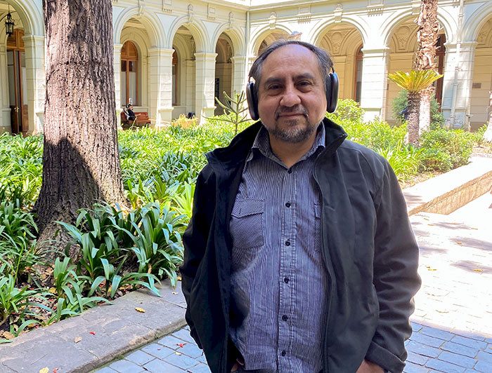 El profesor Rodrigo Cádiz de pie llevando sus audífonos puestos, en un patio de Casa Central de la Universidad Católica.