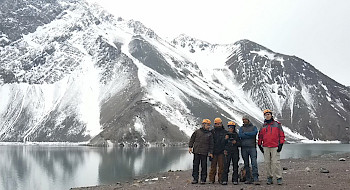 Grupo de investigadores usando cascos y ropa de terreno en el embalse el Yeso, en el Cajón del Maipo.