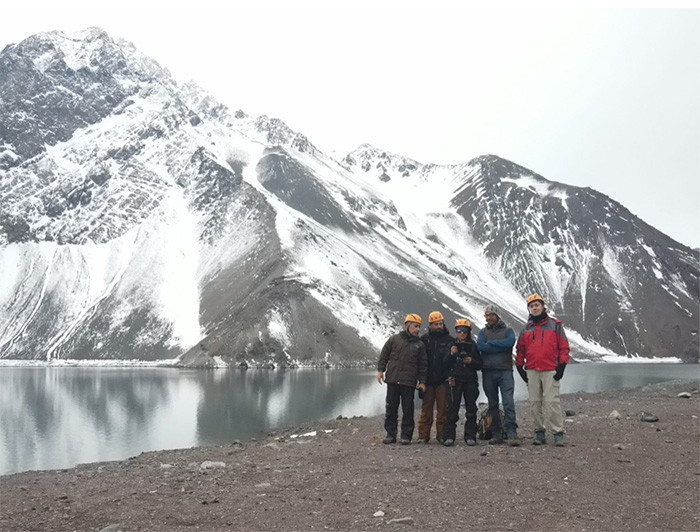 Grupo de investigadores usando cascos y ropa de terreno en el embalse el Yeso, en el Cajón del Maipo.