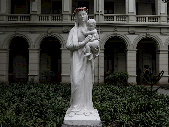 Escultura blanca de la Virgen María con el niño en brazos.