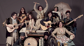Fotografía de una obra de teatro en que se ve un grupo de actores con instrumentos musicales