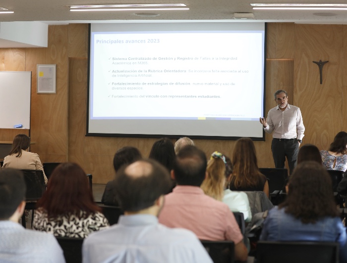 El director académico de docencia Gonzalo Pizarro durante una reunión, exponiendo junto a una pantalla y frente al público en una sala.
