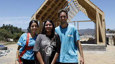 Voluntarios de misiones junto a una joven de la comunidad, de fondo luna capilla en construcción.