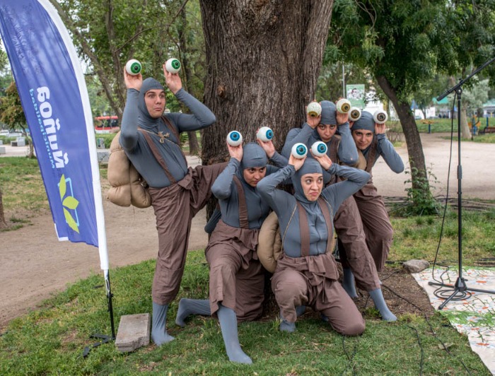 Estudiantes de Teatro disfrazados de caracol en la obra Lento, actuando en una plaza.