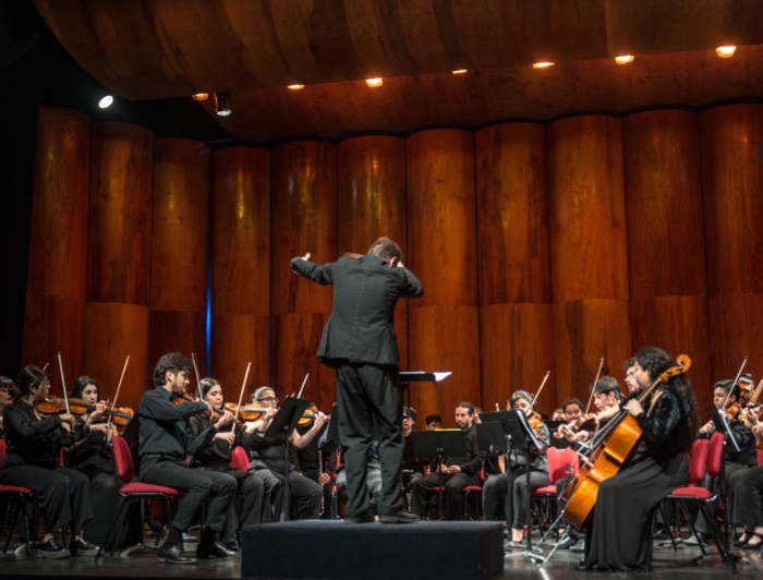 Orquesta de estudiantes UC tocando en el escenario.