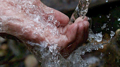 mano de persona mojándose con agua