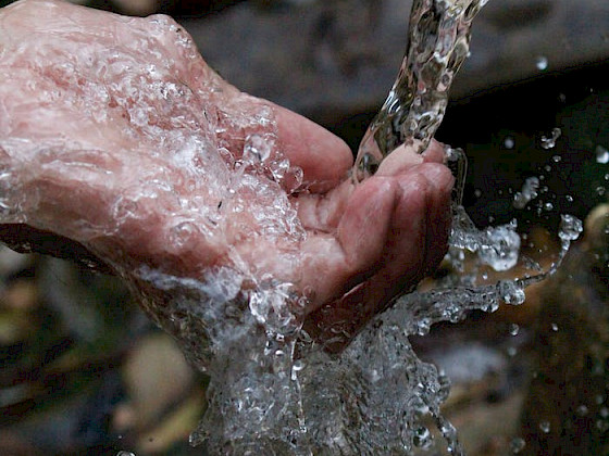 mano de persona mojándose con agua