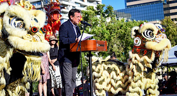Rector UC Ignacio Sánchez hablando en un escenario junto a dos figuras representativas de un león Durante la celebración del Año Nuevo Chino.