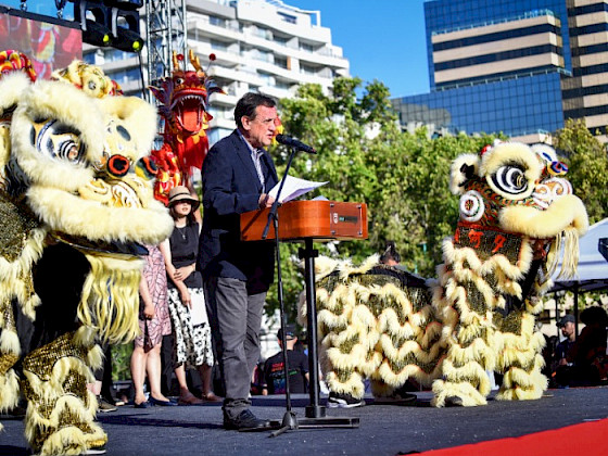 Rector UC Ignacio Sánchez hablando en un escenario junto a dos figuras representativas de un león Durante la celebración del Año Nuevo Chino.