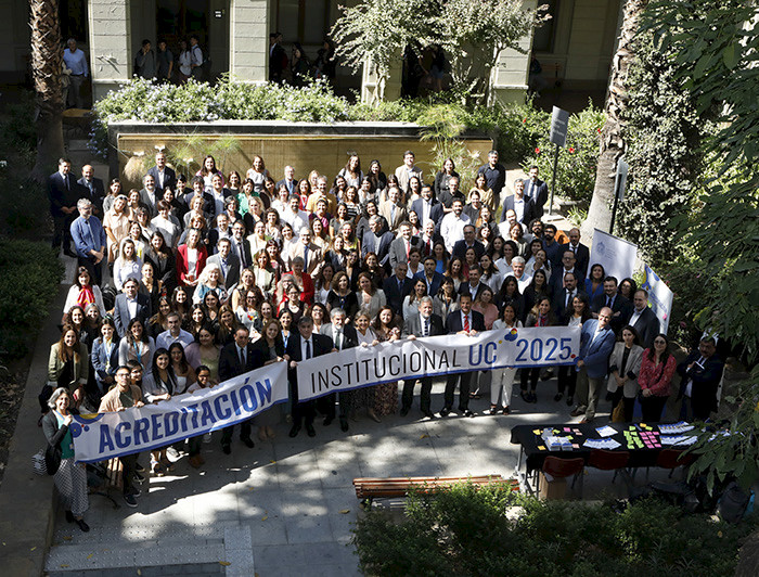 Fotografía de un grupo de personas en un patio de la UC sosteniendo lienzos de Acreditación Institucional UC 2025.