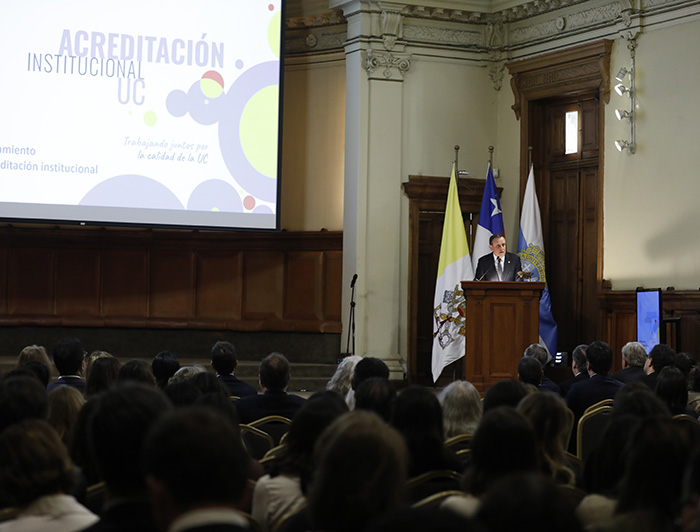 Rector UC Ignacio Sánchez desde un podio y frente a los asistentes, durante la ceremonia de inicio. del proceso de acreditación institucional. 