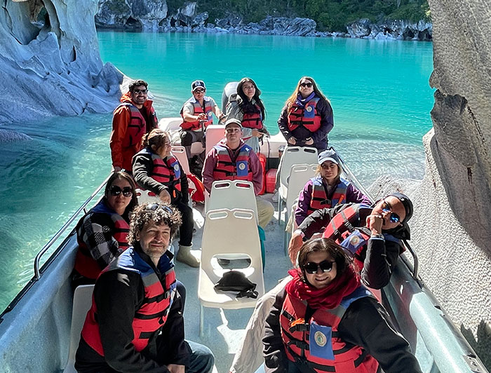 Grupo de la Escuela de Graduados en un bote en un lago y rocas.