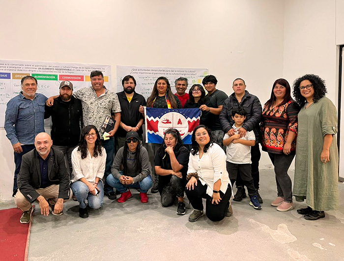 Grupo de personas en una sala sosteniendo al centro la bandera de la comunidad Chango.