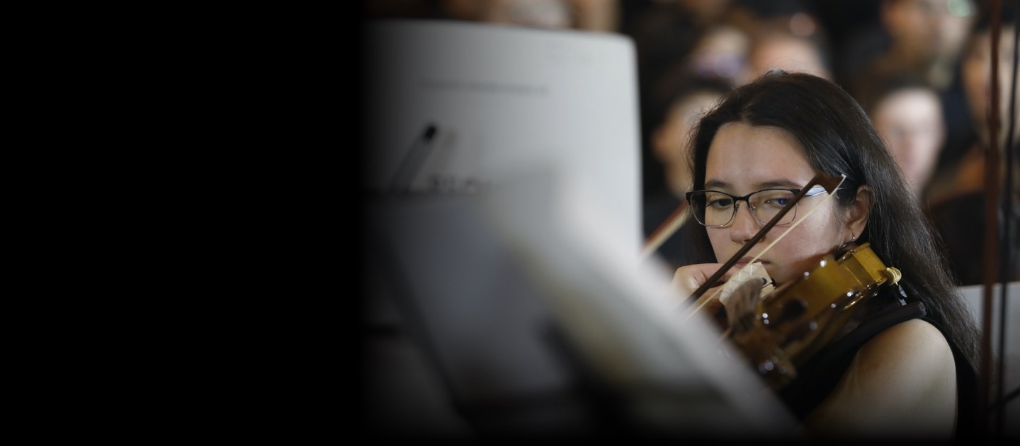 Joven tocando el violín detrás de unas partituras