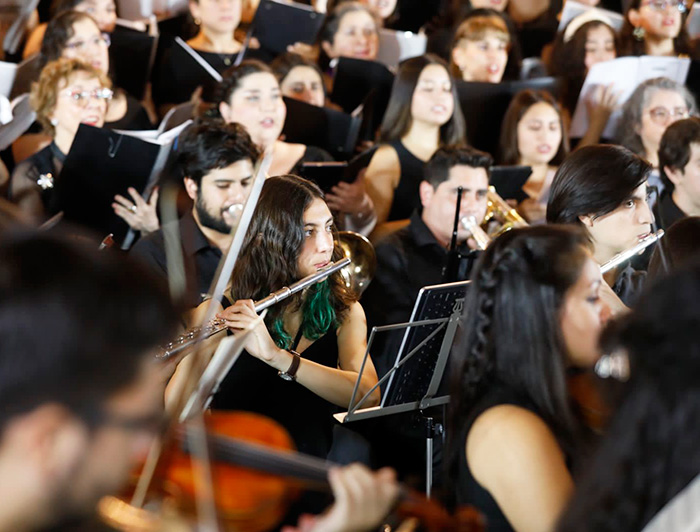 Joven toca la flauta traversa en una orquesta.