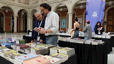 Público revisa los libros de Ediciones UC dispuestos en unos mesones, en el Centro de Extensión UC.