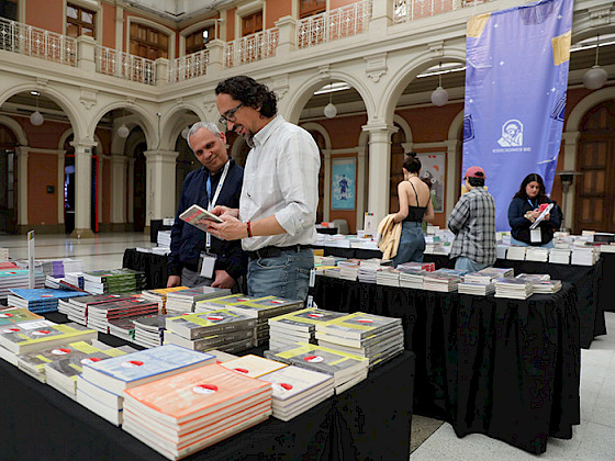 Público revisa los libros de Ediciones UC dispuestos en unos mesones, en el Centro de Extensión UC.