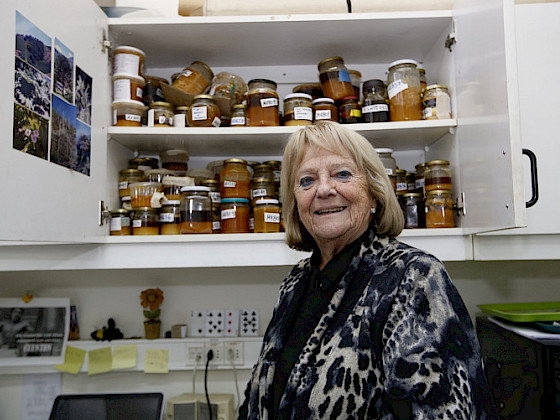 mujer rubia con frascos de miel en mueble a sus espaldas