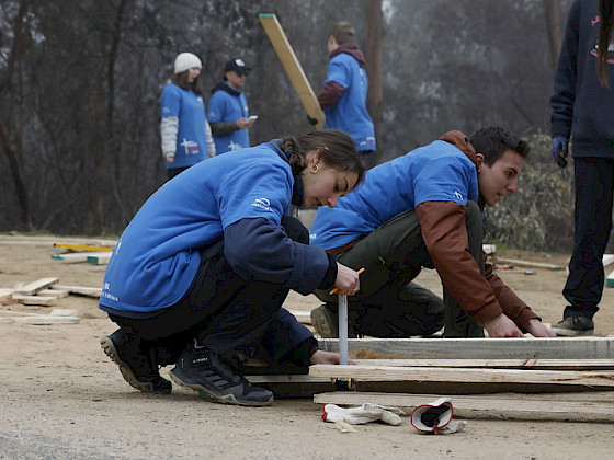 Jóvenes martillan tablas en el suelo.