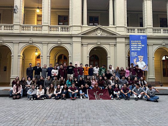 Grupo de 50 jóvenes de pie con una bandera en sus manos.