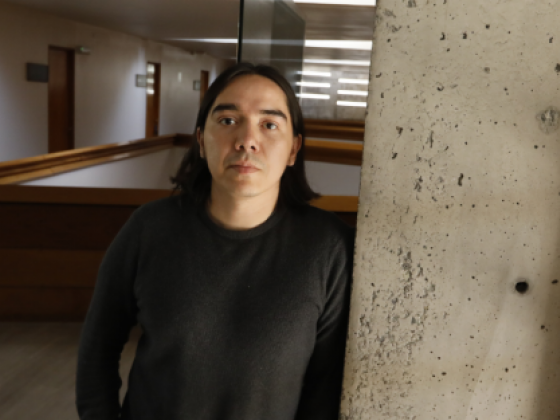 Hombre de pie, junto a una muralla