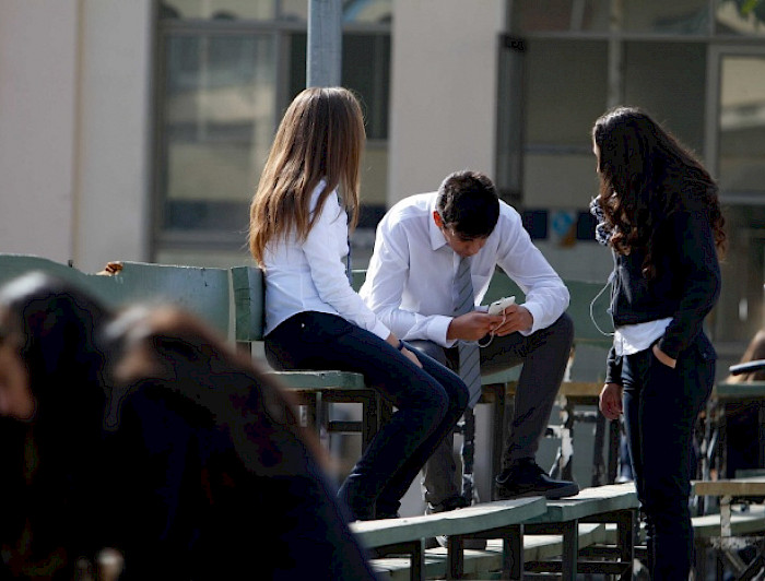 Escolares en patio, revisando el celular