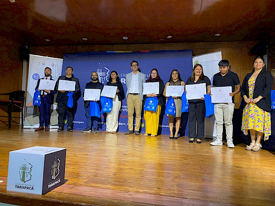 personas sobre un escenario con diploma en la mano