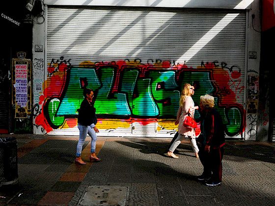 Personas caminando por la calle, de fondo unos grafitis