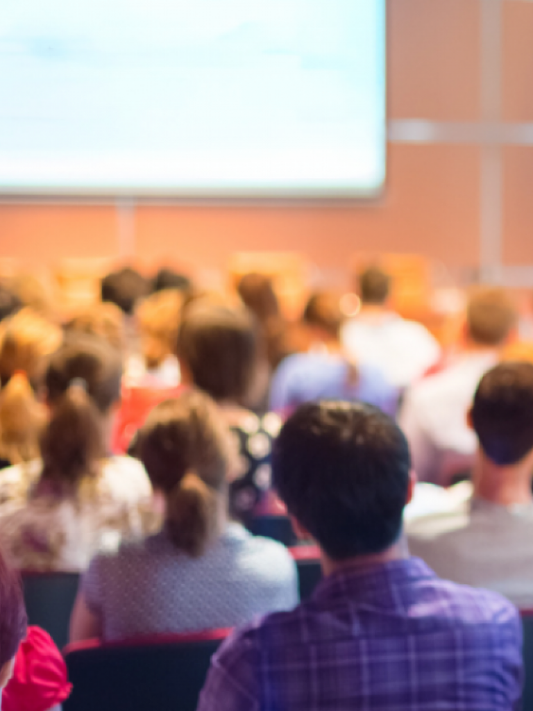 Audience attending a presentation during a professional conference or educational summit in a modern venue.