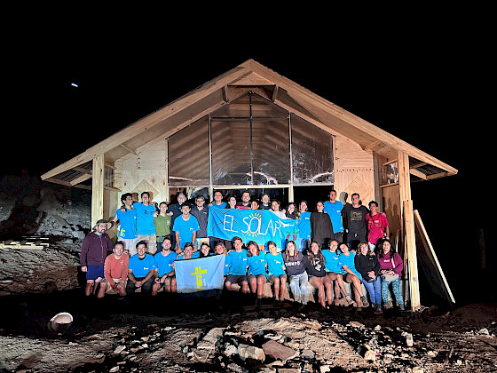 grupo de jóvenes frente a nueva capilla, fondo cielo de noche