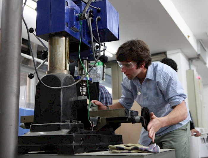 Estudiante utilizando máquina, en el marco del desarrollo científico, tecnológico y de innovación en la UC.