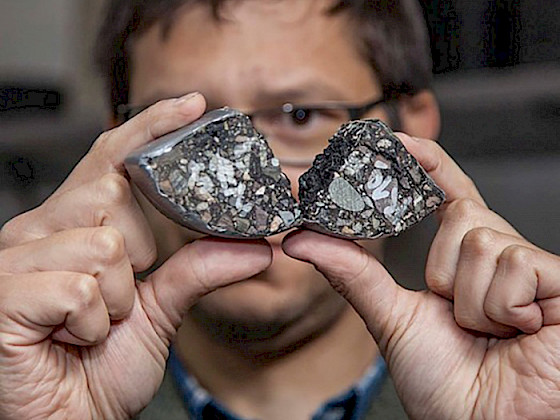 Investigador sostiene en sus manos un trozo de asfalto modificado con lignina.