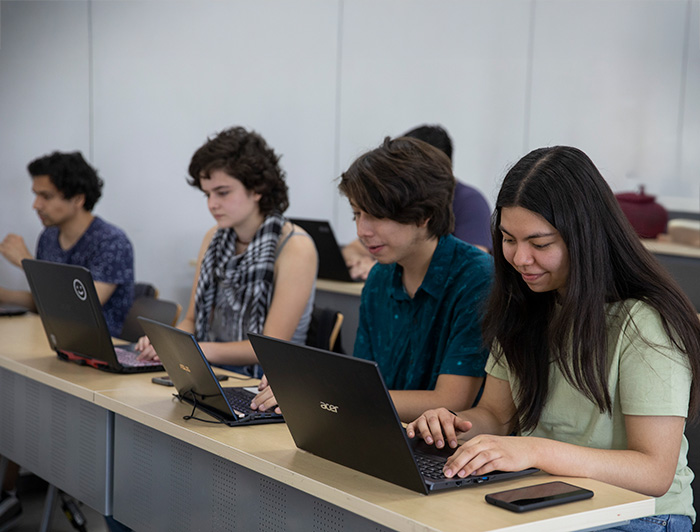 Estudiantes trabajando en sus computadores en una sala de clases.