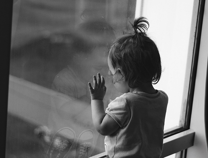 Niña pequeña mirando por una ventana