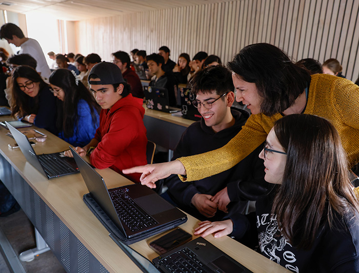 Estudiantes y profesora trabajando con computadores en una sala.