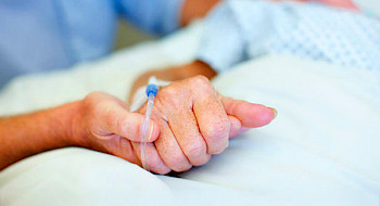 Mano que sostiene la mano de un paciente