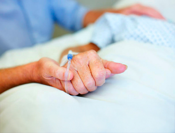 Mano que sostiene la mano de un paciente
