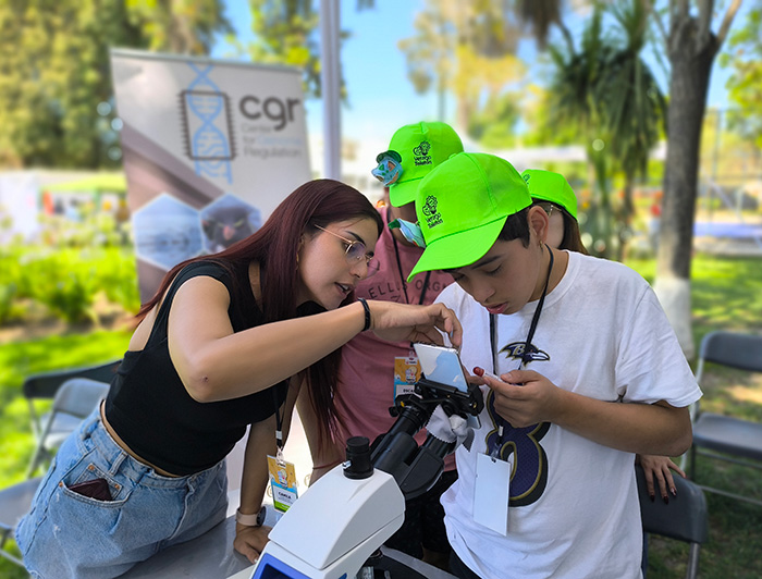 Investigadora orienta a un niño a observar por microscopio.