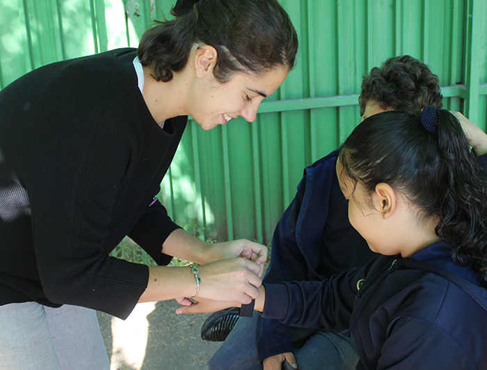 Teresita Reymond colocando una pulsera a una escolar para fomentar la actividad física.
