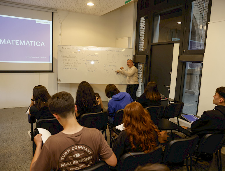 Profesor con pizarra hace clase a alumnos