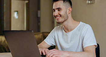 Hombre joven sonriendo frente a un computador