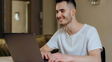 Hombre joven sonriendo frente a un computador