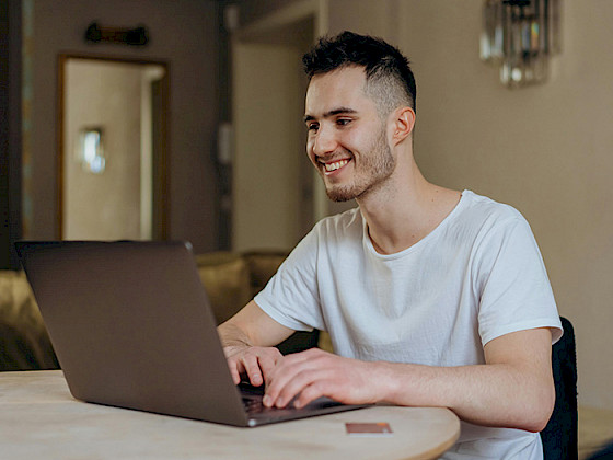 Hombre joven sonriendo frente a un computador
