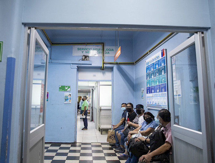 Pacientes sentados en un pasillo de hospital
